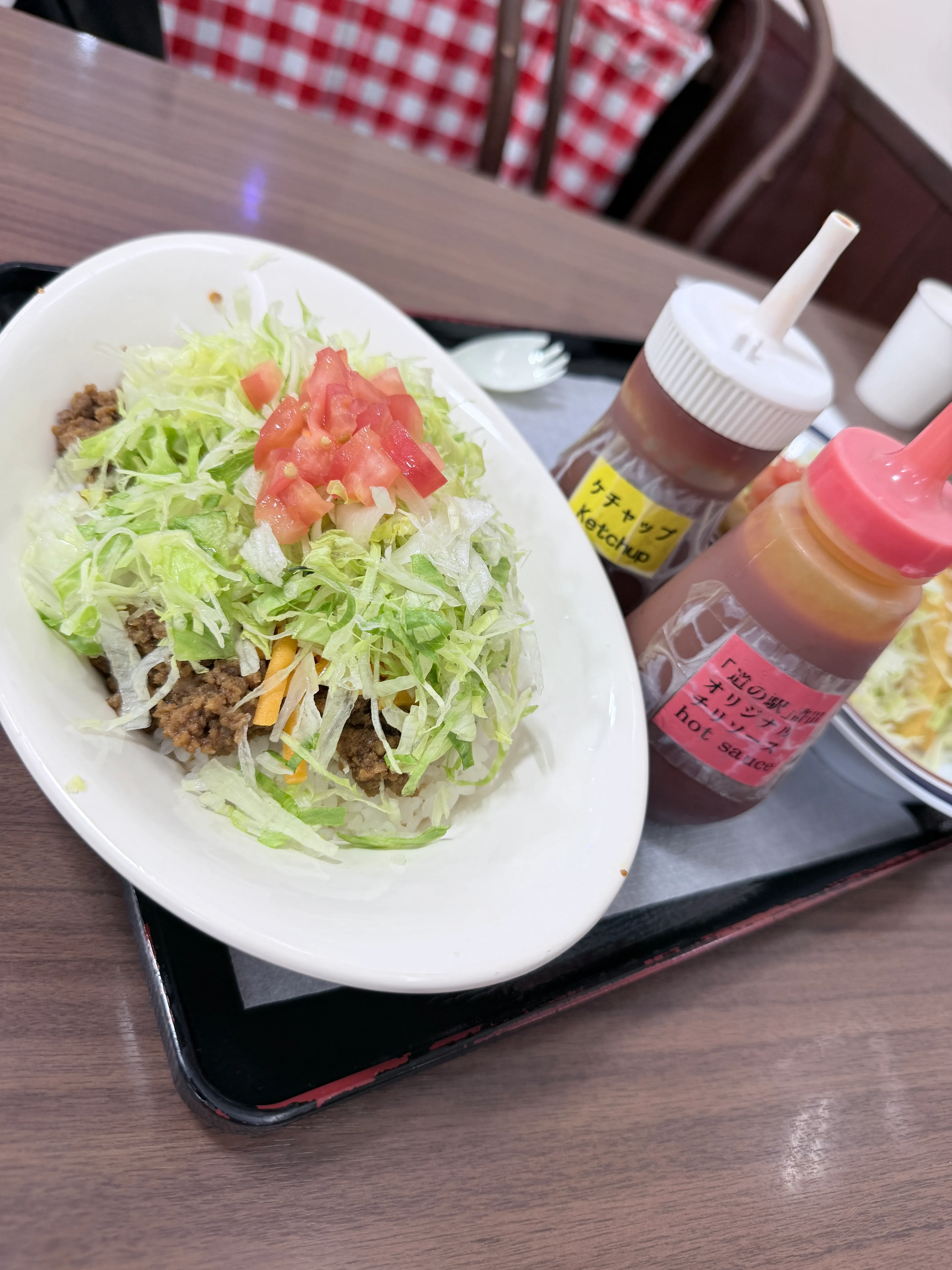 道の駅許田のタコライス。刻んだレタスとトマトがたっぷりのり、オリジナルホットソースとケチャップが添えられている